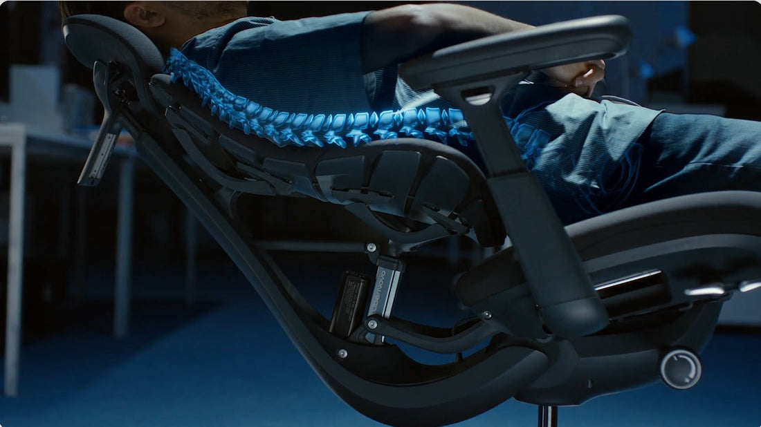 User reclining in LiberNovo Omni ergonomic chair at 160-degree angle, using massage and stretch mode to relieve lower back pain.