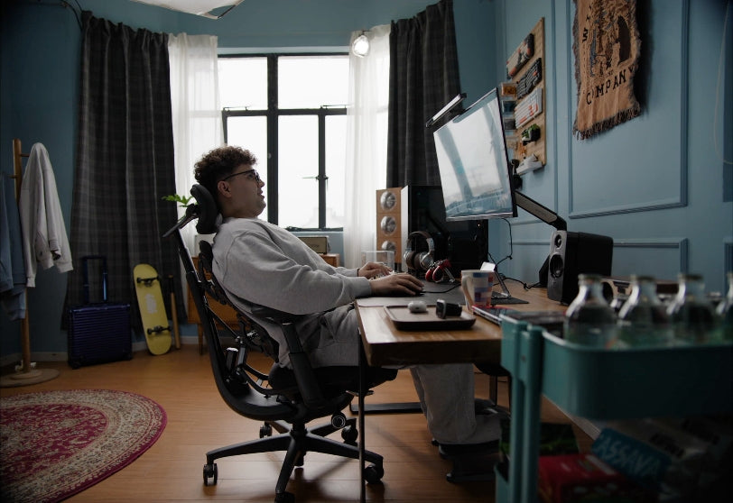 A gamer reclining in the LiberNovo Omni ergonomic chair, fully relaxed while gaming in a cozy bedroom setup.